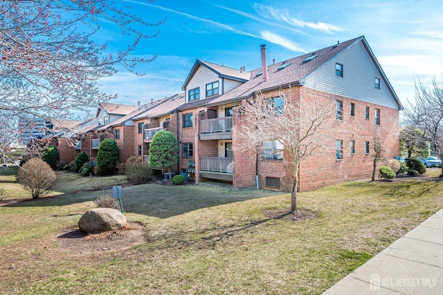 view of side of property with brick siding and a lawn