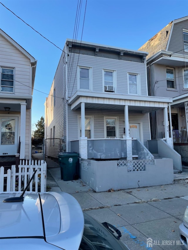 view of front facade featuring covered porch, cooling unit, and fence