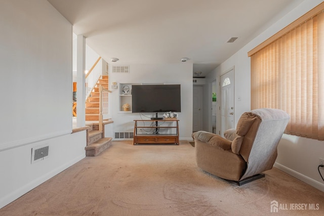 living room with carpet floors, visible vents, and stairs