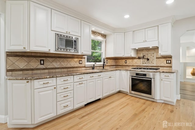 3 Cedar Ln, Milltown, NJ 08850 - kitchen featuring appliances with stainless steel finishes, under cabinet range hood, light wood-style floors, white cabinetry, and decorative backsplash