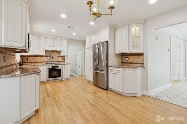 3 Cedar Ln, Milltown, NJ 08850 - kitchen featuring appliances with stainless steel finishes, tasteful backsplash, white cabinetry, a chandelier, and light wood-style flooring