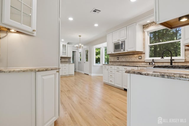 3 Cedar Ln, Milltown, NJ 08850 - kitchen featuring white cabinets, stainless steel microwave, light wood-style flooring, backsplash, and recessed lighting