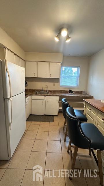 46 Gramercy Gdns, Middlesex, NJ 08846 - kitchen featuring freestanding refrigerator, dark countertops, white cabinetry, and light tile patterned flooring