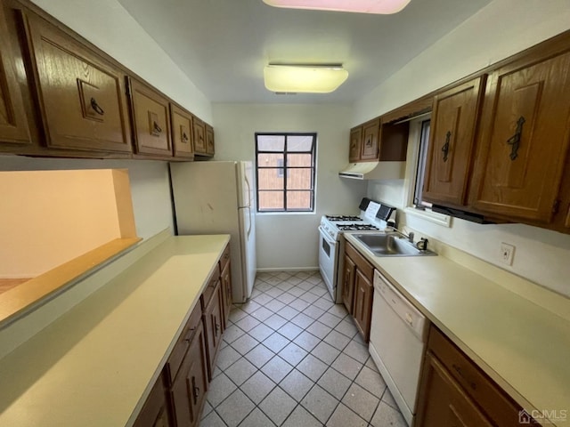 kitchen featuring white appliances, baseboards, light countertops, a sink, and light tile patterned flooring