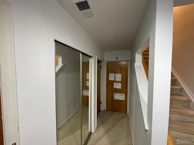 hallway featuring concrete flooring, visible vents, and stairs