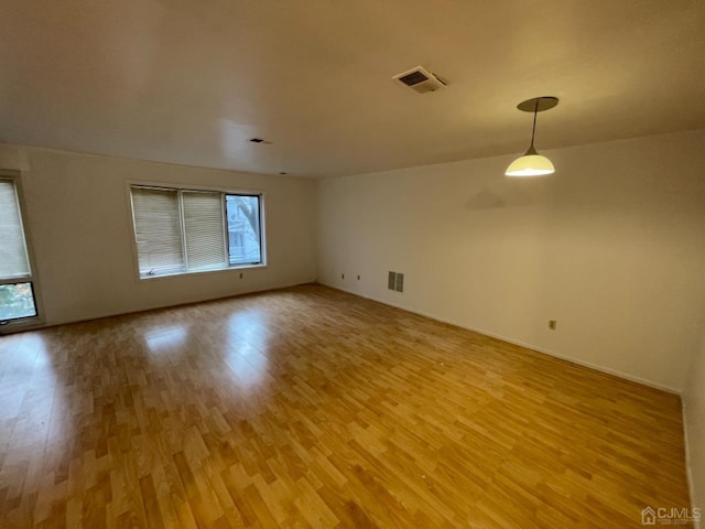 empty room with light wood-style floors, a wealth of natural light, and visible vents