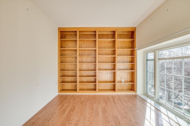 empty room with hardwood / wood-style floors and built in shelves