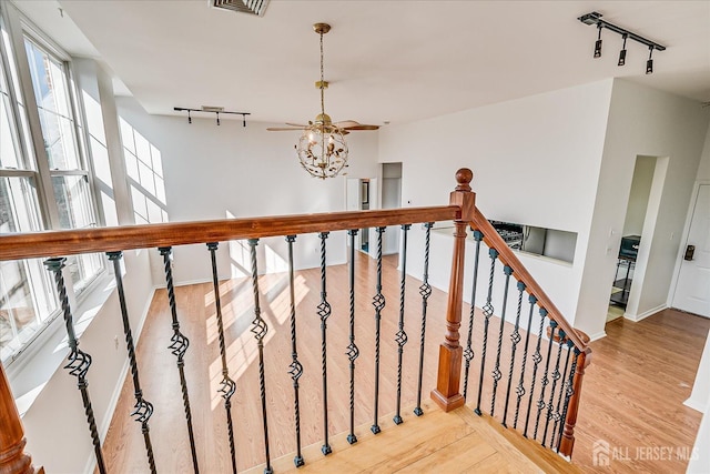 stairs featuring hardwood / wood-style flooring, ceiling fan, and rail lighting