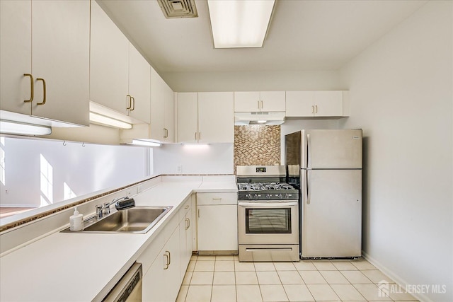 kitchen with sink, light tile patterned floors, appliances with stainless steel finishes, white cabinetry, and tasteful backsplash