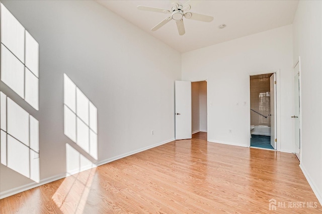 unfurnished room with a high ceiling, ceiling fan, and light hardwood / wood-style floors