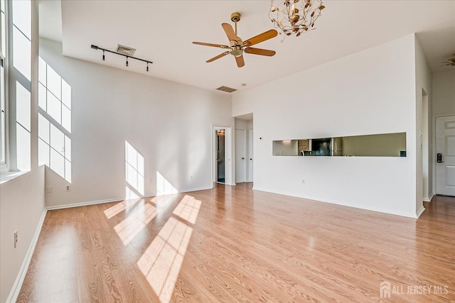 unfurnished living room featuring ceiling fan, track lighting, light hardwood / wood-style flooring, and a towering ceiling