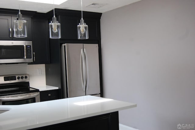 kitchen featuring visible vents, dark cabinets, stainless steel appliances, light countertops, and backsplash