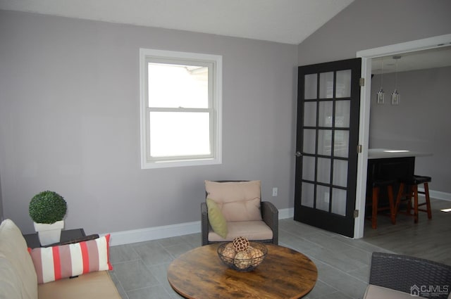 living area featuring lofted ceiling, tile patterned flooring, and baseboards