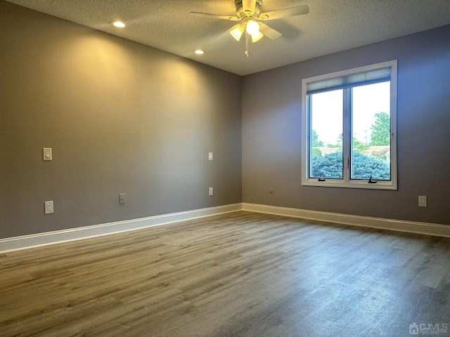 empty room with a textured ceiling, baseboards, and wood finished floors