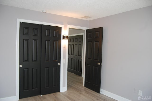 unfurnished bedroom with a closet, a textured ceiling, and light wood finished floors