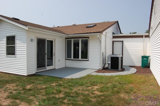 back of property featuring a yard, roof with shingles, cooling unit, and a patio