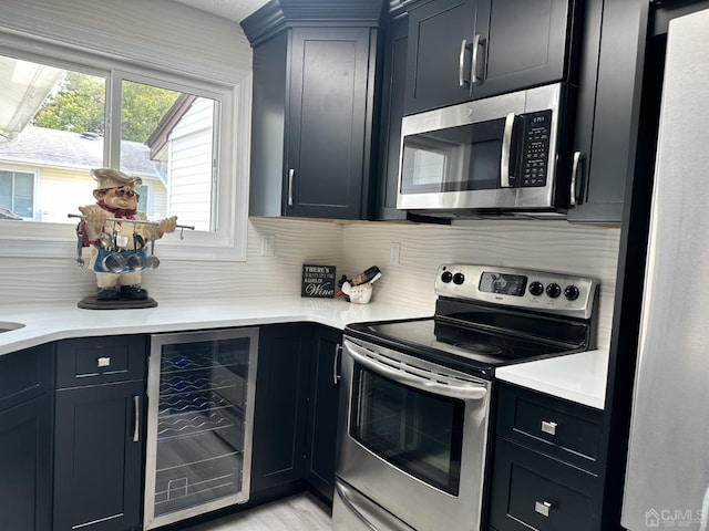 kitchen featuring light countertops, wine cooler, appliances with stainless steel finishes, and tasteful backsplash