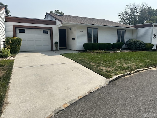 ranch-style home featuring driveway, roof with shingles, an attached garage, and a front yard