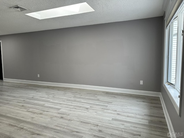 spare room with a skylight, plenty of natural light, and wood finished floors