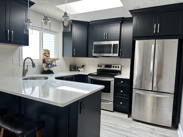 kitchen with a breakfast bar area, stainless steel appliances, a peninsula, a sink, and light countertops