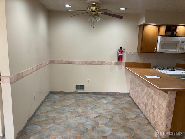 134 Hatfield Ln, East Brunswick, NJ 08816 - kitchen featuring white microwave, ceiling fan, recessed lighting, light countertops, and brown cabinetry