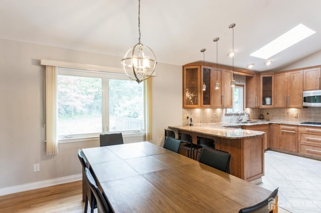 14 Agate Rd, East Brunswick, NJ 08816 - dining space featuring a chandelier, lofted ceiling, baseboards, a skylight, and light wood-style floors