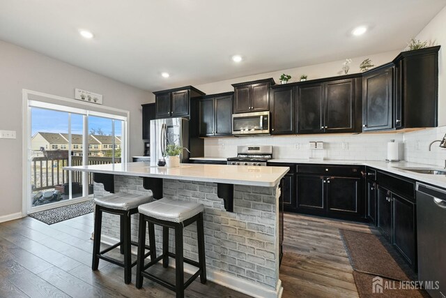 kitchen featuring decorative backsplash, a center island, dark wood-type flooring, and appliances with stainless steel finishes