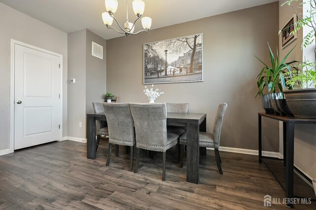 dining room with dark hardwood / wood-style flooring and a chandelier