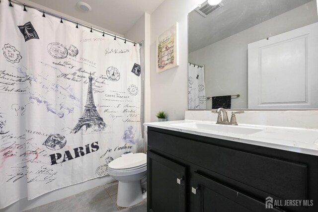 bathroom with toilet, vanity, and tile patterned floors