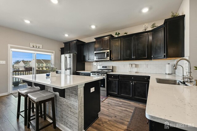 kitchen featuring dark hardwood / wood-style floors, stainless steel appliances, decorative backsplash, a kitchen island, and sink