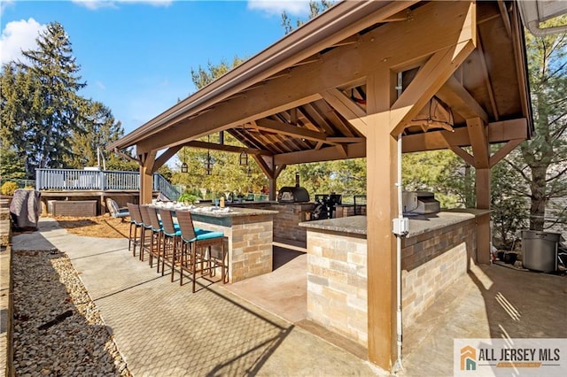 view of patio featuring a gazebo, an outdoor kitchen, area for grilling, and a bar