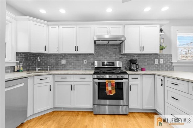 kitchen with sink, light hardwood / wood-style flooring, stainless steel appliances, range hood, and white cabinets