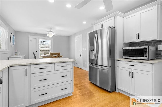 kitchen featuring tasteful backsplash, white cabinets, ceiling fan, light hardwood / wood-style floors, and stainless steel appliances