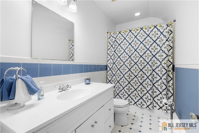 bathroom with a shower with curtain, vanity, tile walls, and toilet