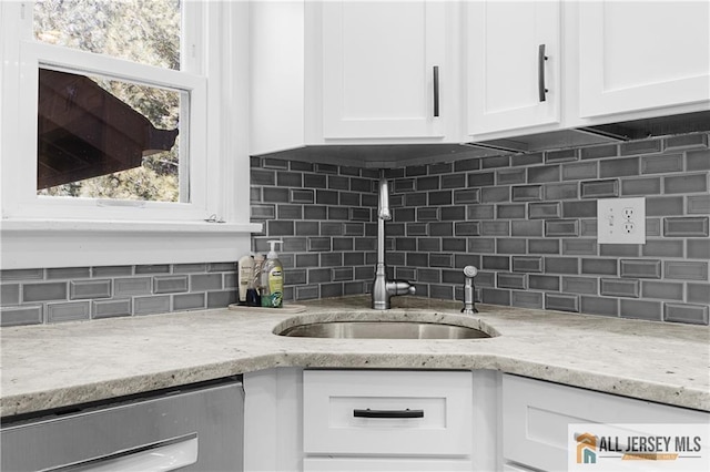 kitchen featuring sink, tasteful backsplash, dishwasher, light stone countertops, and white cabinets