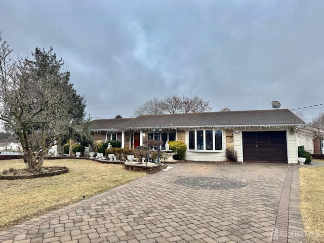 ranch-style home featuring a garage and a front lawn