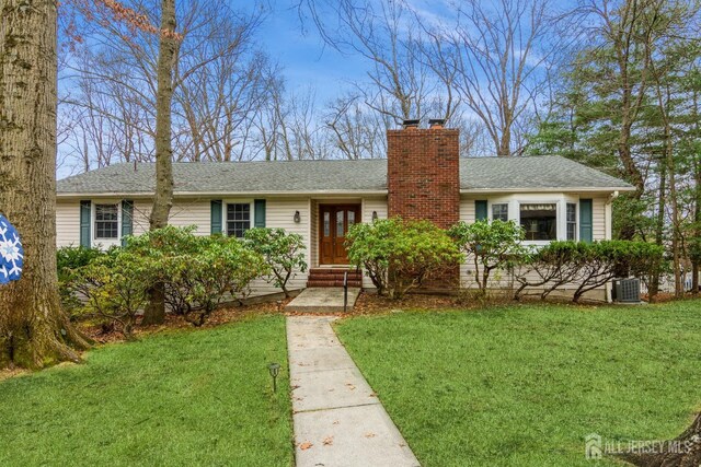 ranch-style home with central air condition unit and a front lawn