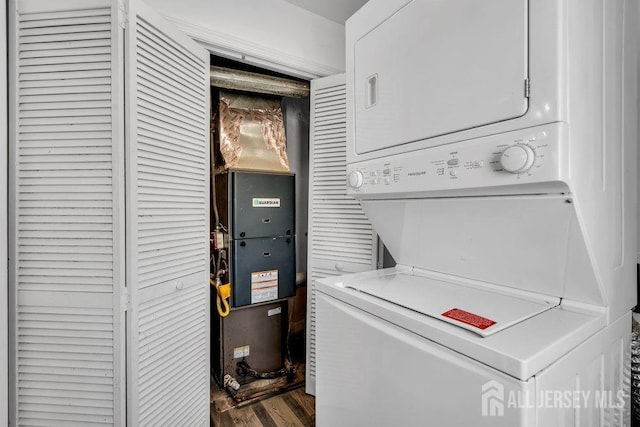 laundry room with stacked washer / drying machine, laundry area, and dark wood finished floors