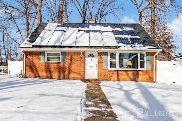 view of front of house with fence, solar panels, and brick siding