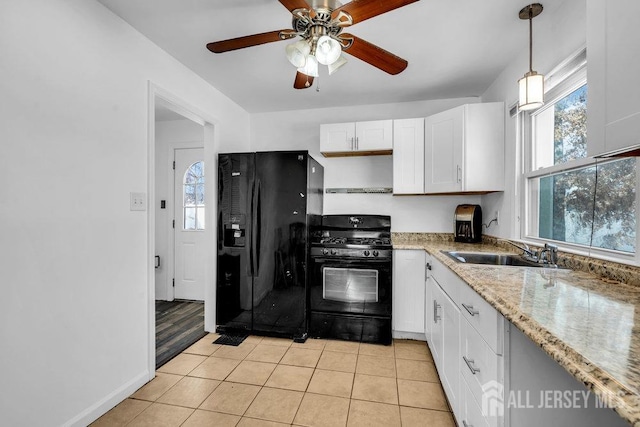 kitchen with sink, light tile patterned floors, hanging light fixtures, black appliances, and white cabinets