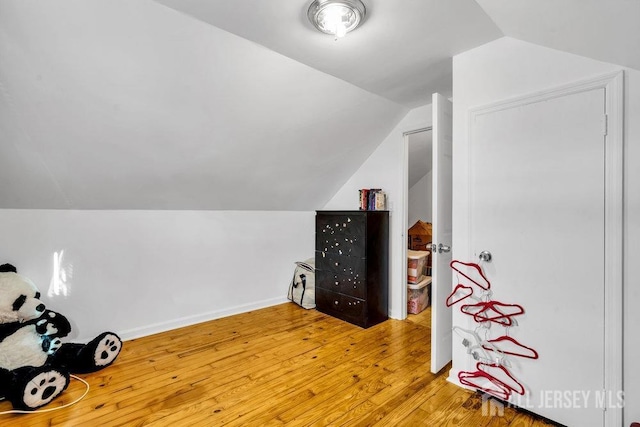 additional living space with hardwood / wood-style flooring and vaulted ceiling