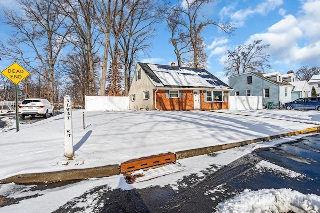 view of front of house with roof mounted solar panels, fence, and brick siding