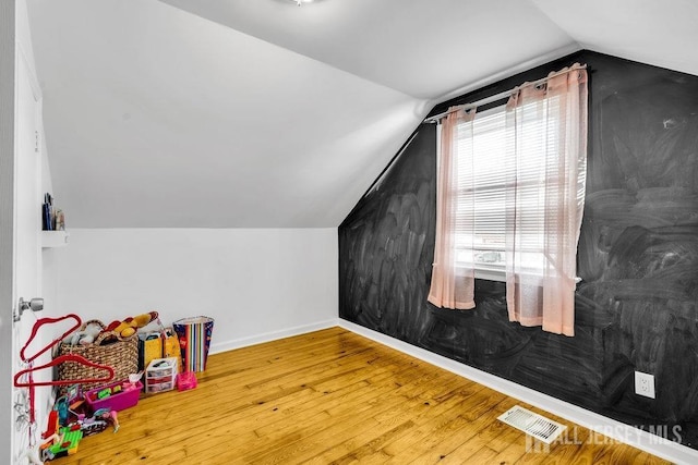 additional living space with hardwood / wood-style flooring and lofted ceiling