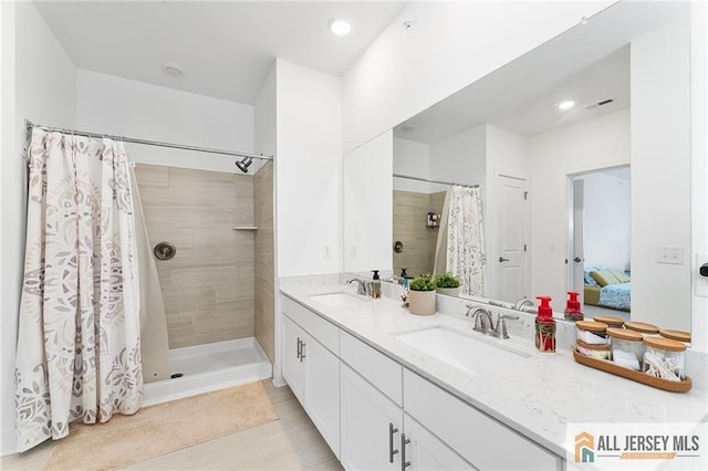 ensuite bathroom with double vanity, a stall shower, connected bathroom, and a sink