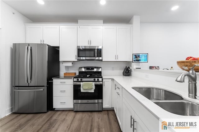 kitchen featuring recessed lighting, stainless steel appliances, dark wood-style flooring, a sink, and white cabinets