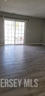 empty room featuring baseboards, wood finished floors, and a wealth of natural light