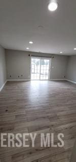 empty room with baseboards, recessed lighting, and wood finished floors