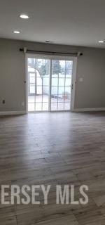 unfurnished room featuring recessed lighting, baseboards, plenty of natural light, and wood finished floors
