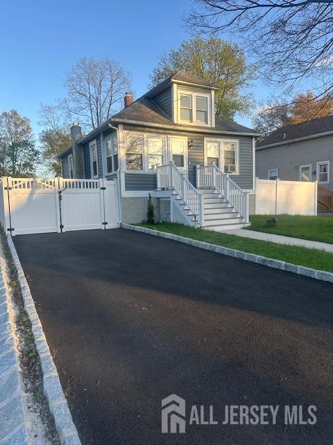 view of front facade featuring a gate, fence, and a chimney