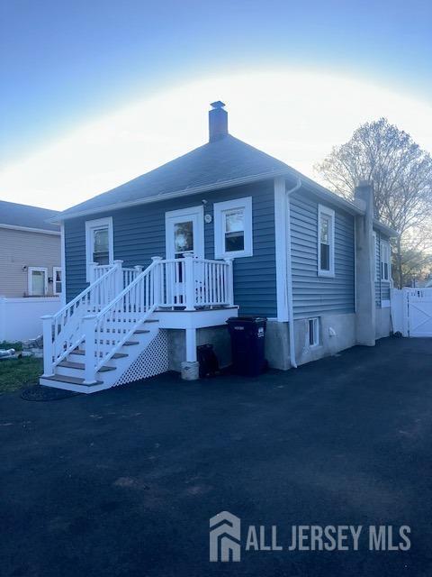 back of house with fence and a chimney